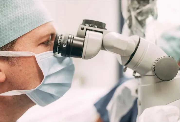 Zahnarzt bei einer endodontischen Behandlung unter dem Mikroskop in der Zahnarztpraxis Sandhofpassage Frankfurt – präzise Wurzelkanalbehandlung mit modernster Technologie