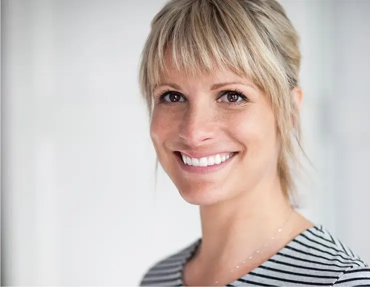 Porträt einer lächelnden Frau mit weißen, geraden Zähnen. Die Nahaufnahme betont das Ergebnis einer ästhetischen Zahnbehandlung, die ein gesundes und schönes Lächeln zeigt.