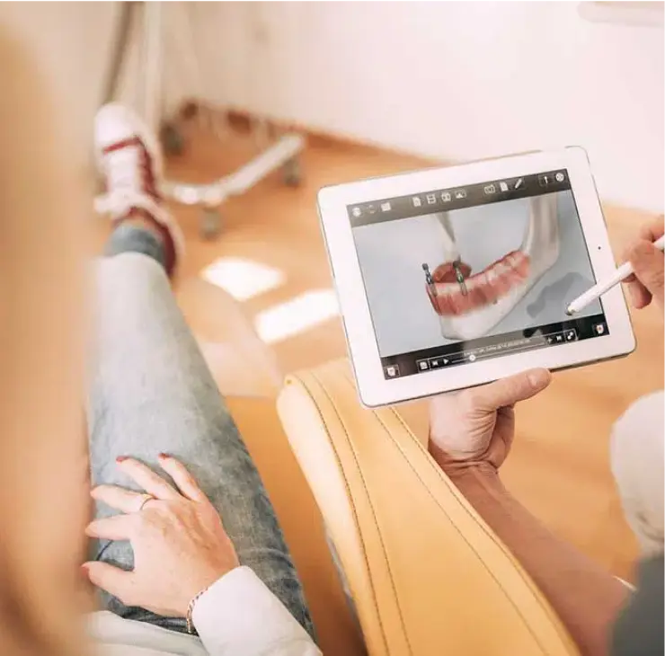 Patientin sieht sich den digitalen Implantationsprozess auf einem Tablet in der Zahnarztpraxis Sandhofpassage Frankfurt an.
