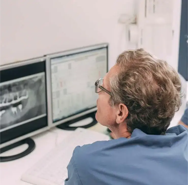 Zahnarzt überprüft Röntgenbild zur Beurteilung von Zahnimplantaten bei einem Patienten in der Zahnarztpraxis Sandhofpassage Frankfurt.