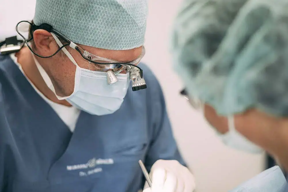 Zahnarzt bei einer chirurgischen Behandlung in der Zahnarztpraxis Sandhofpassage Frankfurt – präzise Zahnbehandlungen mit modernster Technologie